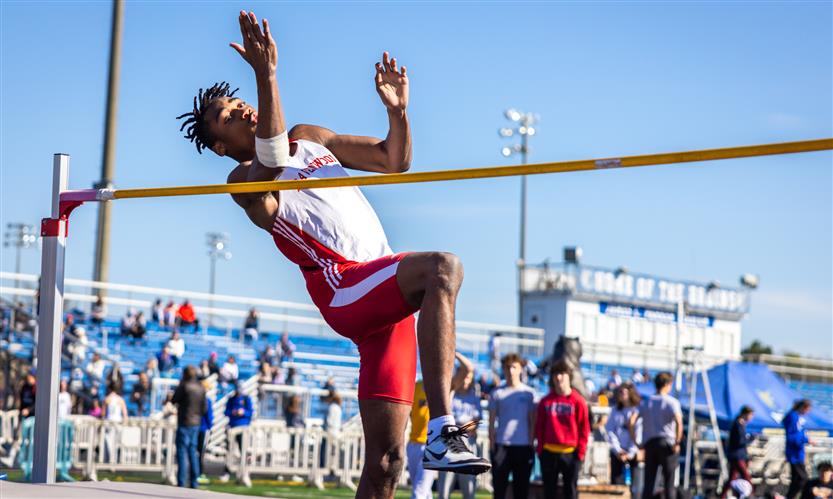 A student jumps over a bar